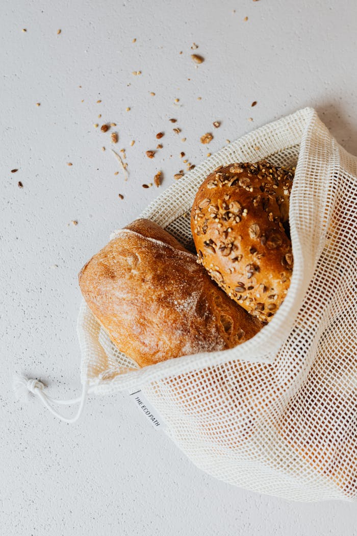 Close-up of freshly baked artisanal bread in a reusable net bag, emphasizing zero waste lifestyle.